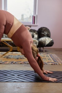 woman doing the downward dog yoga pose in her living room
